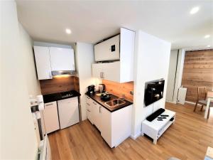 a small kitchen with white cabinets and a wooden floor at Grand Studio Aiguille du Midi et vue Mont Blanc in Chamonix-Mont-Blanc