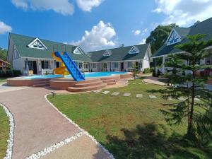 a house with a slide in front of a swimming pool at English Resotel : อิงลิช รีโซเทล in Nakhon Si Thammarat