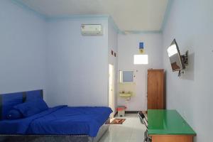 Un dormitorio con una cama azul y un escritorio verde. en Angrumba Family Homestay near RSUD Caruban Mitra RedDoorz, en Mejayan