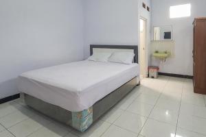 1 cama en un dormitorio con suelo blanco en Angrumba Family Homestay near RSUD Caruban Mitra RedDoorz, en Mejayan