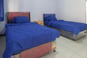 2 camas con sábanas azules en una habitación en Angrumba Family Homestay near RSUD Caruban Mitra RedDoorz, en Mejayan