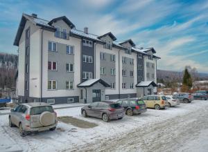 a large building with cars parked in a parking lot at Retro Bieszczady in Ustrzyki Dolne