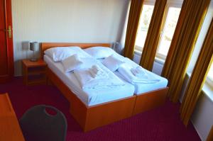 1 dormitorio con 1 cama con sábanas blancas y ventana en Hotel Evan u Hoffera, en Topoľčany