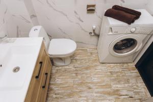a bathroom with a toilet and a washing machine at LUXE Apartments Illinskaya 3 floor in Sumy