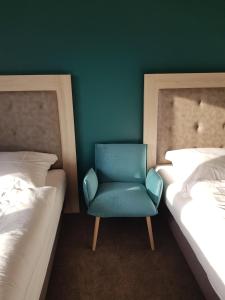 a blue chair sitting between two beds in a room at Boardinghouse am Borkumkai in Emden