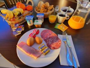 a table with a plate of food with eggs meat and bread at Hôtel Azur Saint Junien Cit'Hotel in Saint-Junien