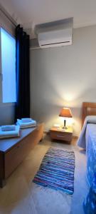 ein Schlafzimmer mit einem Bett, einer Lampe und einem Teppich in der Unterkunft Apartamentos Serrallo, Parking gratuito y cocina, Alhambra y playa in Granada