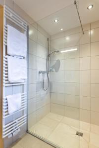 a bathroom with a glass shower with white towels at Gasthaus Posch in Miesbach