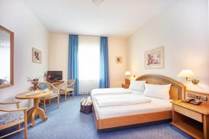 エタールにあるホテル クローステルホーテル ルートヴィヒ デア バイエルのベッド、テーブル、椅子が備わるホテルルームです。