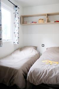 twee bedden naast een raam in een slaapkamer bij Mobil Home XXL 4 chambres - Camping Les Pins in Erquy