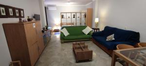 ein Wohnzimmer mit einem blauen Sofa und einem grünen Stuhl in der Unterkunft Apartamentos Serrallo, Parking gratuito y cocina, Alhambra y playa in Granada
