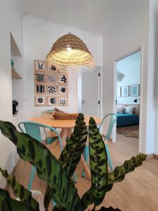 a dining room with a table with chairs and a plant at Largo A2 in Alcácer do Sal