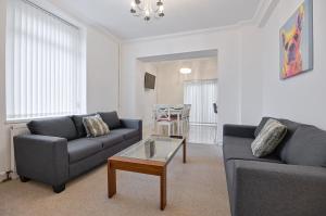 a living room with two couches and a coffee table at Spacious home with parking - TV in Every Bedroom! in Swansea