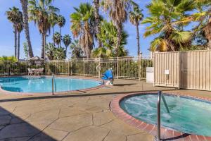 a swimming pool with a fence and palm trees at Comfort Inn & Suites Huntington Beach in Huntington Beach