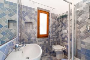 a blue tiled bathroom with a toilet and a sink at Ginestre S in La Maddalena