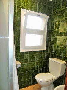 a bathroom with a toilet with a window and green tiles at Apartament ARTS 3 in L'Estartit