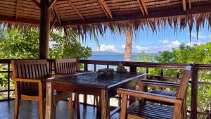 Pulau MansuarNyande Raja Ampat的门廊上的一张桌子和几把椅子，可以看到海景
