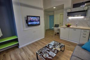 a living room with a couch and a tv on a wall at 1926 Designed ApartHotel in Haifa