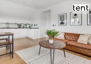 Stylish & Comfy 1 Bed Apt by Tent Serviced Apartments Egham - Town centre with parking and Wifi في ايجهام: غرفة معيشة مع أريكة وطاولة