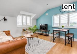 a living room with blue walls and a couch and tables at Stylish & Comfy 1 Bed Apt by Tent Serviced Apartments Egham - Town centre with parking and Wifi in Egham