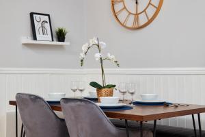 une table à manger avec des chaises et une horloge murale dans l'établissement Central Harrogate 2 Bedroom Apartment, à Harrogate