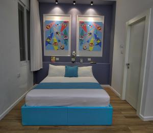 a bedroom with a blue bed with two pictures on the wall at 1926 Designed ApartHotel in Haifa