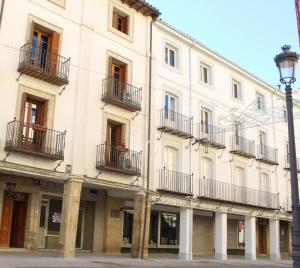 a large white building with balconies and a street light at La Corredera in Úbeda