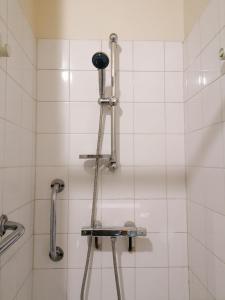 La salle de bains est pourvue d'une douche et de carrelage blanc. dans l'établissement EK Studio Appartement, à Saint Etienne