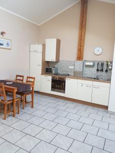 - une cuisine avec des placards blancs, une table et des chaises dans l'établissement Am Valtlhof, à Grabenstätt