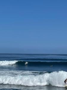 a person riding a wave on a surfboard in the ocean at Villa Atlántida. Precioso apartamento con ventanas al mar in Santa Maria de Guia de Gran Canaria