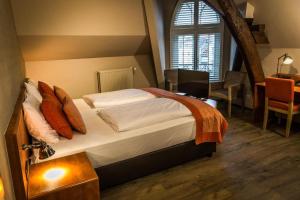 a bedroom with a bed and a desk and a window at Hotel De Limbourg in Sittard