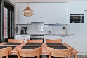 a kitchen with white cabinets and a wooden table and chairs at Holiday in Lapland - SointuiLevi A71 in Levi
