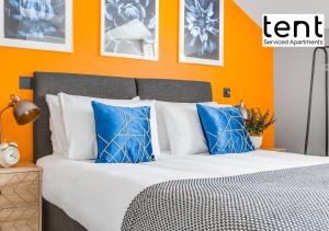 埃格姆Central 1 BR apt , pkg, great for long term guests的橙色卧室配有蓝色枕头的床