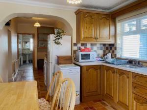 eine Küche mit Holzschränken und einem weißen Kühlschrank in der Unterkunft Cottage 397 - Carna in Carna