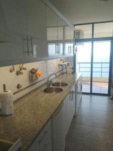 eine Küche mit einem Waschbecken und einem großen Fenster in der Unterkunft Edifício Panorâmico - Falésia de Sesimbra in Sesimbra