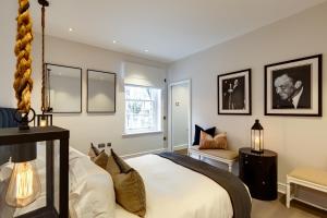1 dormitorio con 1 cama blanca grande y 1 silla en Flawless Eight-bedroom Cheyne Family home in the heart of Chelsea en Londres