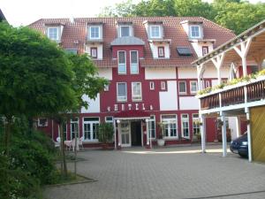 a large red and white building with a courtyard at Cross-Country-Hotel Hirsch in Sinsheim