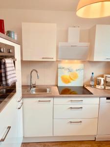 una cucina con armadi bianchi e lavandino di City Apartment 09 a Itzehoe