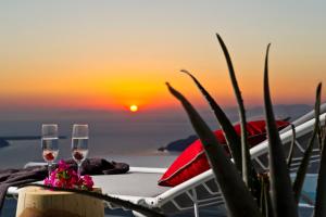 two glasses of wine on a table with the sunset in the background at Avista Suites in Imerovigli