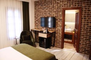 een hotelkamer met een televisie en een bakstenen muur bij Pintura Urla Hotel in Urla