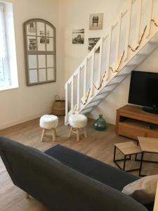 uma sala de estar com uma escada com duas cadeiras e uma televisão em Appartement cosy en duplex à 50m de la plage em Le Portel