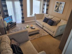 een woonkamer met 2 banken en een televisie bij The Meridan Lodge - Platinum 2024 Season in Clacton-on-Sea