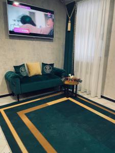 sala de estar con sofá verde y TV de pantalla plana en Green Garden Hotel en Kol'chugino