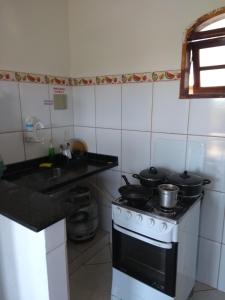 a kitchen with a stove with pots and pans on it at Wando Suítes in Búzios