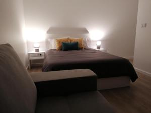 1 dormitorio con 1 cama con 2 lámparas y 1 sofá en Refúgio do Norte, en Calhetas