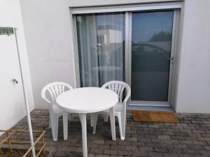 una mesa blanca y 2 sillas en el patio en Refúgio do Norte, en Calhetas