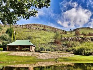 a house on a hill next to a body of water at Trout River Falls in Lydenburg