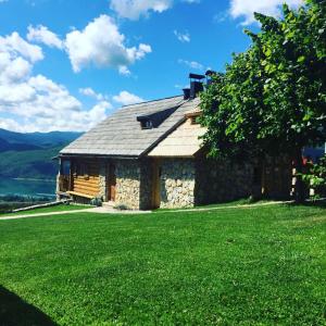 ein Steinhaus mit grünem Rasen davor in der Unterkunft Seoska kuca Vidikovac in Prozor