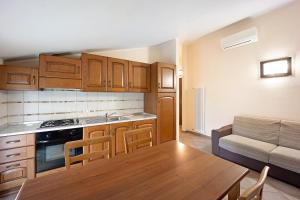 a kitchen with wooden cabinets and a table and a couch at Virginia Agriturismo La Scuderia in Molino Nuovo