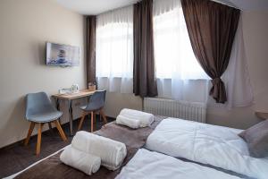 a bedroom with a bed and a desk and a window at City Panzió in Szarvas